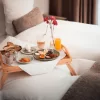 Breakfast tray on the bed with egg, cheese, juice and coffee – late-riser breakfast at Hotel Bellerive Zermatt.