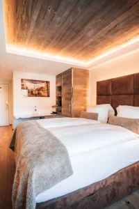 Chambre double Cosy Chic à l'Hôtel Bellerive Zermatt avec lit queen-size, plafond en bois et éclairage indirect