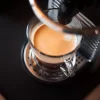 Espresso mit goldener Crema im Glas auf der Abtropfschale einer Kapselmaschine, Nespresso-Kaffee im Zimmer inklusive im Hotel Bellerive Zermatt.