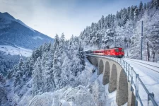 Train rouge sur un viaduc en pierre enneigé parmi les sapins, arrivée alpine vers Zermatt, Hotel Bellerive Zermatt.