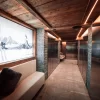 Heated ski depot with metal lockers, stone floor, timber ceiling and a bench at Hotel Bellerive Zermatt.