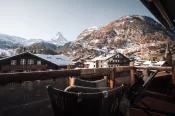 Holzbalkon mit Liegestühlen, Blick auf verschneites Zermatt und das Matterhorn vom Sky Room.