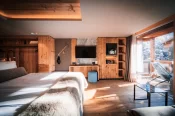 Wood cabinetry with TV, ice-axe décor and snowy balcony in the Panorama Deluxe Room at Hotel Bellerive Zermatt.