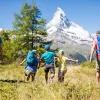 Family hiking a summer alpine meadow toward the Matterhorn; children up to 9 years stay free at Hotel Bellerive Zermatt.