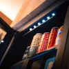 Offener Minibar-Kühlschrank mit Farmer-Bier, Coca-Cola, Fanta und LED-Licht im Holzschrank, inklusive für Direktbucher im Hotel Bellerive Zermatt.