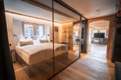 Double bed behind a glass partition with white linens in The Alpine Nest 1895 at Hotel Bellerive Zermatt.