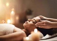 Woman with eyes closed receiving a head massage, white towels and candlelight in the spa, Hotel Bellerive Zermatt.
