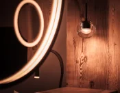 Round LED mirror and glass globe pendant against wood panelling in the Panorama Deluxe Room, Hotel Bellerive Zermatt.