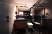 Salle de bain avec vasque, miroir encadré bois et douche walk-in vitrée dans le Sky Room à Zermatt.