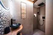 Salle de bain avec vasque noire, mosaïque hexagonale et douche walk-in dans l'Alpine Nest 1895 à Zermatt.
