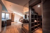 Overhead view of Junior Suite Chic: wooden shelves with a safe, mirrored wardrobe, sofa under a skylight and balcony view of Zermatt.