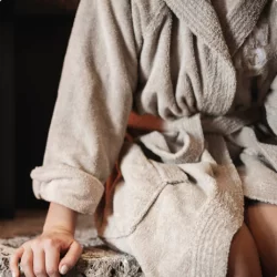 Invité en peignoir éponge beige, main sur la pierre, moment bien-être des offres à l'Hôtel Bellerive Zermatt.