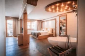 Junior Suite mit freistehender Badewanne, Doppelbett in Holznische und runder Deckenleuchte, Hotel Bellerive Zermatt.