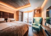 Cosy Chic double room with bed, turquoise armchair and balcony view at Hotel Bellerive Zermatt