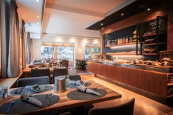 Frühstücksraum mit gedecktem Holztisch und beleuchtetem Buffet mit Broten im Hotel Bellerive Zermatt