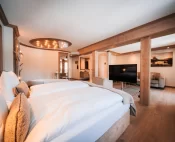 Junior Suite mit Doppelbett, freistehender Badewanne, Holzbalken und Wohnbereich mit Sofa im Hotel Bellerive Zermatt.