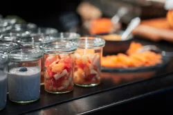 Nahaufnahme von Joghurt- und Fruchtgläsern neben Räucherlachs am Frühstücksbuffet im Hotel Bellerive Zermatt