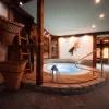 Runder Indoor-Whirlpool mit blauem Licht, Holzdeck und Steinfussboden im Spa des Hotel Bellerive Zermatt.