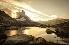Cervin dans une lumière dorée au-dessus d’un lac alpin, vététistes au bord, région de Zermatt.