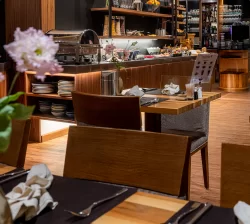 Tables en bois dressées face au buffet petit-déjeuner avec céréales à l'Hôtel Bellerive Zermatt.