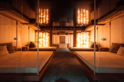 SPA-Ruheraum mit vier hängenden Holzliegen an Seilen und orangefarbenen Salzsteinwänden, Hotel Bellerive Zermatt.