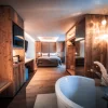 Suite with freestanding bathtub, double bed and wooden wardrobe with a BELLERIVE bag, image for the best-price guarantee at Hotel Bellerive Zermatt.