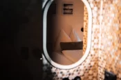 Miroir ovale à LED et mosaïque hexagonale reflétant le lit dans l'Alpine Nest 1895 à Zermatt.