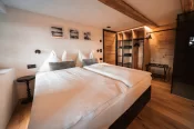 Lit double, dressing en bois éclairé et porte-bagages dans l'appartement Alpine Nest 1895 à Zermatt.