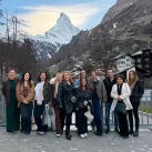 The team of Hotel Bellerive Zermatt posing on a bridge with the snow-capped Matterhorn behind them